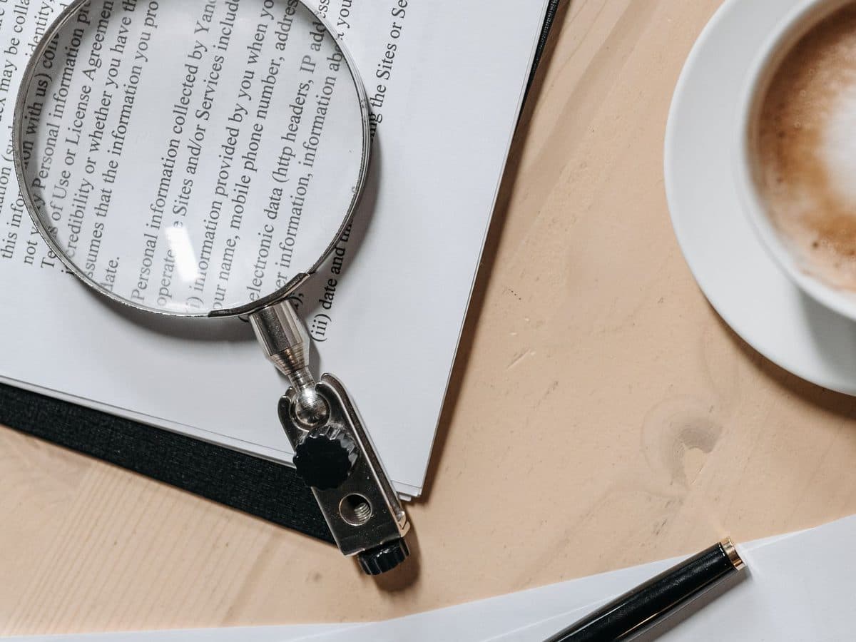 Magnifying glass resting on printed documents beside a pen